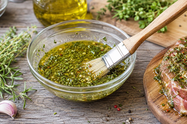 Schüssel mit selbstgemachter Kräuter-Grillmarinade und Pinsel