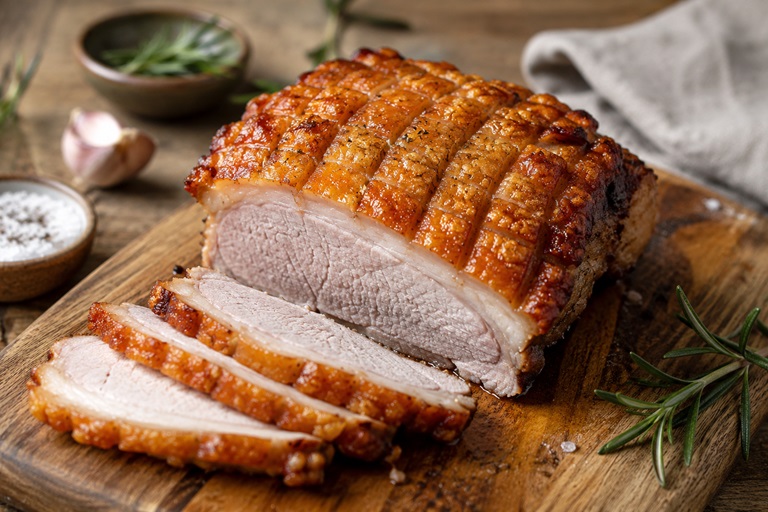 Schweinsbraten mit Kruste, aufgeschnitten auf einem Fleischbrett.