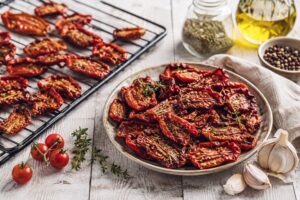 Tomaten trocknen - getrocknete Tomate auf Backofen-Gitter und auf einen Teller.