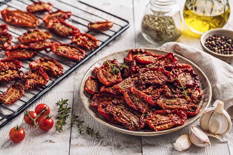 Tomaten trocknen - getrocknete Tomate auf Backofen-Gitter und auf einen Teller.